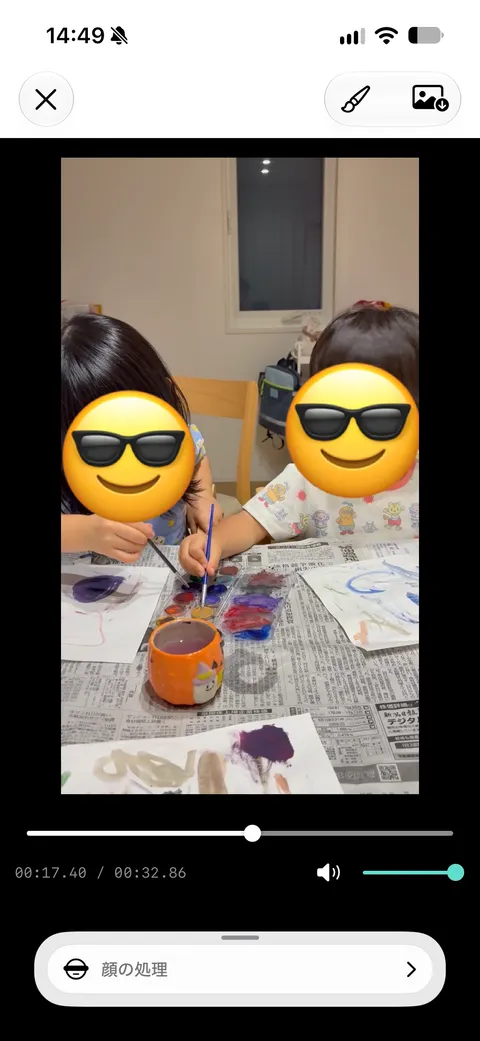 iPhone editor showing emoji covering faces in a video of children painting